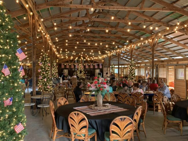 Inside of barn decorated with lights and set with tables and chairs
